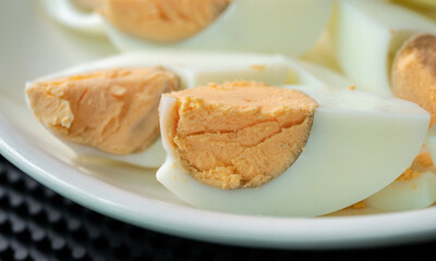 Close up of a pieces of cut boiled eggs serving on white plate.
