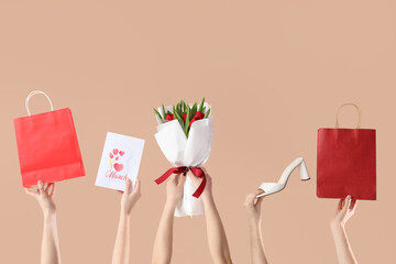 Female hands with bouquet of tulips, shopping bags and high heel shoe on beige background....