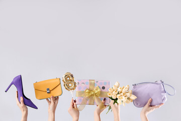Female hands with gift box, tulips and handbags on white background. Shopping for International Women's Day