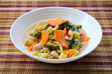 Capcay, stir-fried vegetables with meatballs, sausages and chicken. Served on a white plate
