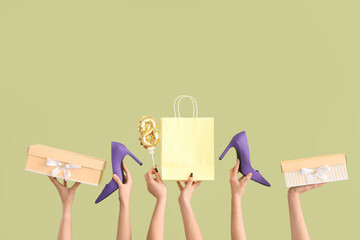 Female hands with gift boxes, high heel shoes and shopping bag on green background. International...