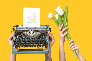 Hands holding vintage typewriter, tulips and festive postcard with text 8 MARCH HAPPY WOMEN'S DAY...
