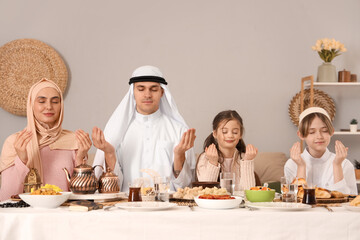 Muslim family praying before dinner at home. Ramadan celebration