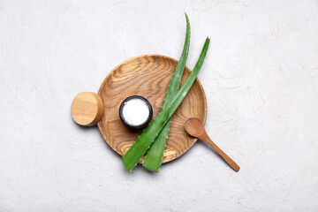 Fototapeta na wymiar Wooden plate with jar of cosmetic product and aloe vera leaves on grey background