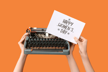 Female hands with retro typewriter and greeting card for International Women's Day on color...