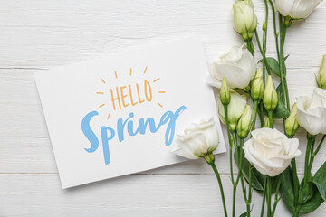 Greeting card with text HELLO SPRING and beautiful eustoma flowers on white wooden background