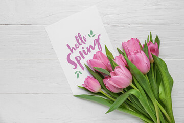 Greeting card with text HELLO SPRING and beautiful pink tulips on white wooden background