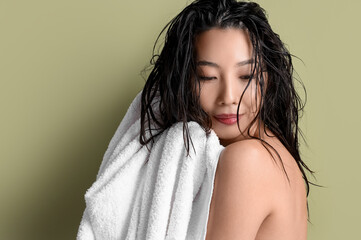 Young Asian woman wiping wet hair with towel on green background, closeup