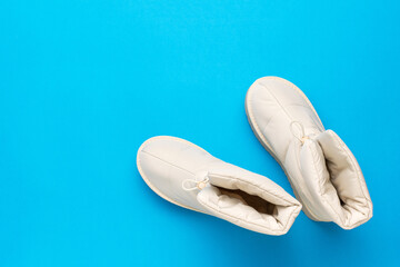 Top view of a pair of beige insulated women's shoes on a light blue background.