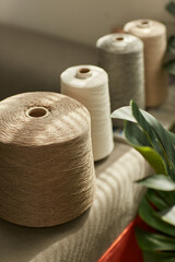 Brown and gray textile linen threads, coils intertwined, illuminated by sunlight indoors
