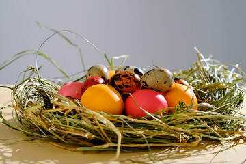 Easter eggs in pink, yellow and orange colors in a nest of grass.