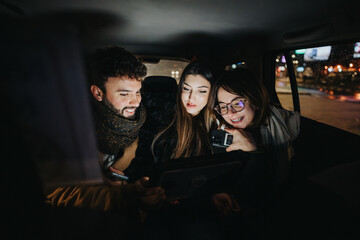 Young adults collaborating on a project at night inside a car.