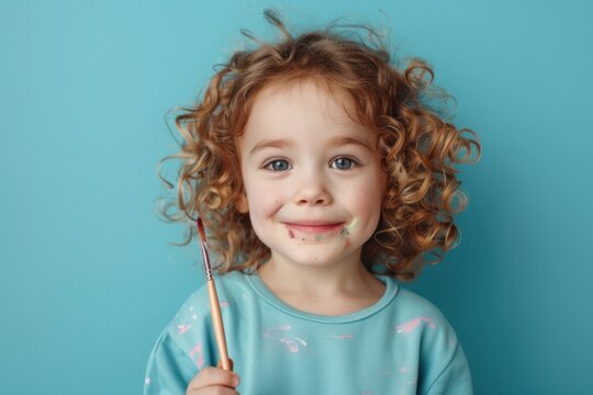 cute kid holding paint brush on blue color background