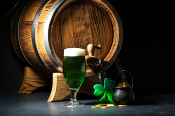 Glass of green beer with barrel, pot full of coins, horseshoe and clover leaf on black background....