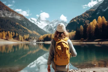 Foto op Canvas Young Woman with Backpack Standing on Mountain Peak, Admiring Winter Landscape and Reflective Lake on Sunny Day, Hiking Adventure © RBGallery