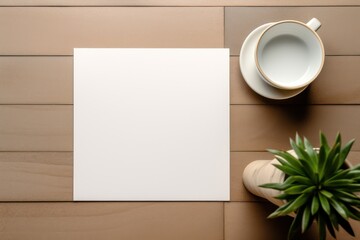 Blank paper copy space template with minimalist interior potted plant decoration and coffe mug on a wooden table. Stationary mock up top view flat lay style.
