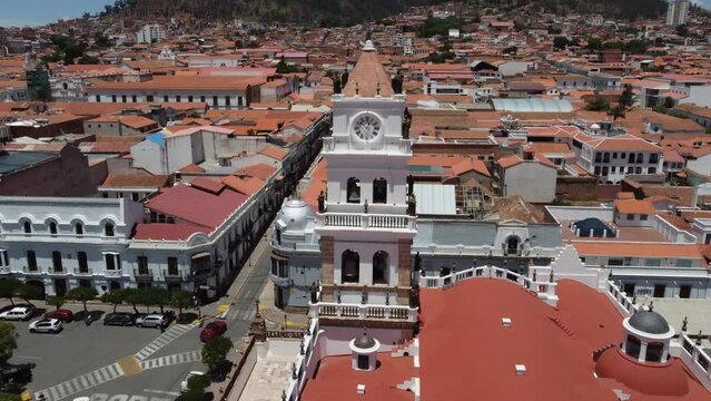 Aerial closely orbits clock tower statues on Sucre Basilica in Bolivia