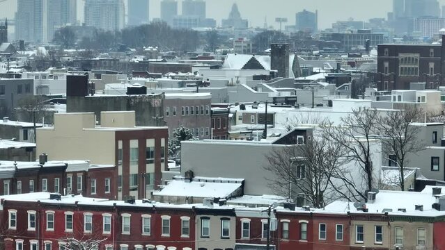 Row houses in snowy city. Aerial reveal of skyline of large American city during winter.