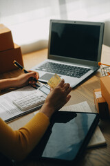 Young woman holding a smartphone, tablet showing payment success and credit card with yellow parcel box as online shopping concept in office