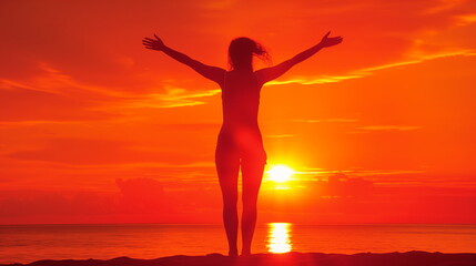 Fototapeta premium Silhouette of a person with outstretched arms facing the sunrise on the beach.