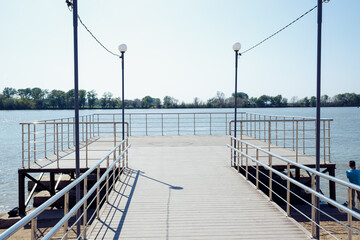 Obraz premium pleasure observation pier, Modern pier on public city beach of lake without people on sunny day