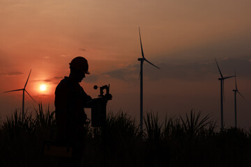 Fototapeta na wymiar Silhouette of young men engineer standing checking equipment wind turbine beside agricultural sugarcane and wind turbine morning sunlight