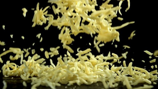 Shredded cheese falling on black background. Filmed on a high-speed camera at 1000 fps. High quality FullHD footage