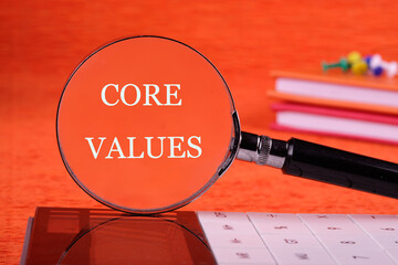 CORE VALUES word written through a magnifying glass on an orange background