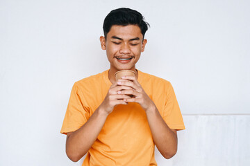 Asian young man drinking takeaway coffee from paper cup