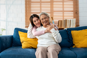Portrait of Asian senior father sitting on sofa with daughter in house. 