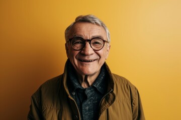 Obraz premium Happy senior man with glasses on yellow background. Looking at camera.