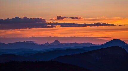 Fototapeta premium Silhouettes of majestic peaks under a sky ablaze with sunset colors