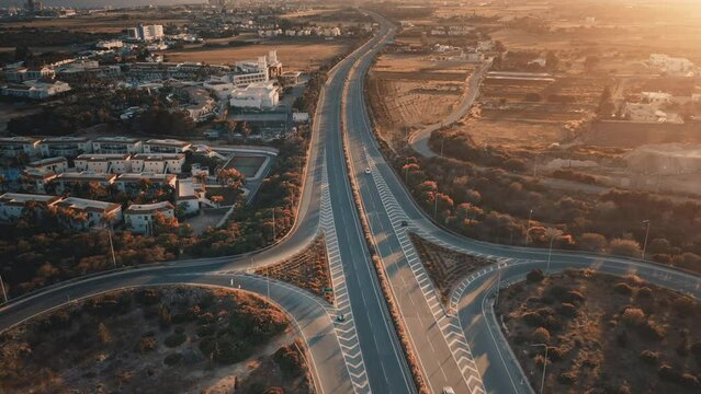 Highway road aerial view. Sunset drone flying over new asphalt road junction overpass with moving cars. Calm countryside landscape. Transportation and travel destinations. Summer vacation.
