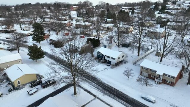 Aerial view of snow-covered neighborhood with roads, trees, and houses at twilight. American houses in winter.