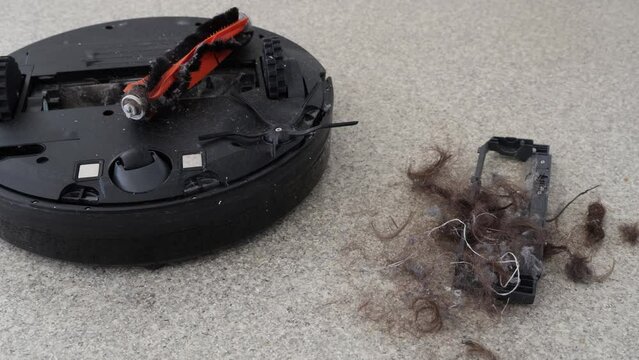 Broken robot vacuum and pile of dirt and tangled hair