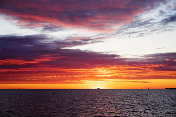 sunrise or sunset over the sea with brightly colorful clouds in the blue sky