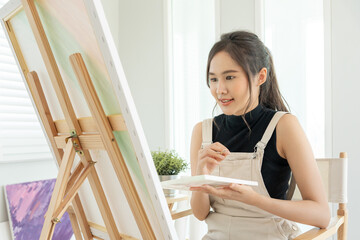beautiful female hobbies about artist and use paintbrush in abstract art for create masterpiece. painter paint with watercolors or oil in studio house. enjoy painting as hobby, recreation, inspiration