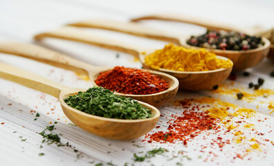 Set of various powder spices in a wooden spoon isolated on white background. Collection of close-up wooden spoons with chili powder, curry, tumeric, cumin, pepper powder. Clipping path. - obrazy, fototapety, plakaty