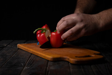 Cutting vegetables. Male hands cutting sweet red pepper on cutting board.