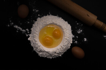 Eggs, flour and cutlery on black