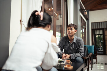 Smiling young Asian man friend talking and sharing massage experience in spa salon. Two Asian people talking in lobby.