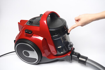 Finger presses the button of a red vacuum cleaner