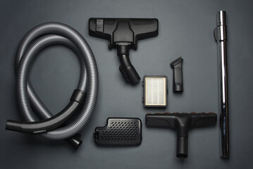 Components and attachments of a modern vacuum cleaner on dark background. Top view. Flat lay