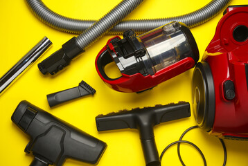 Components and attachments of a modern vacuum cleaner on yellow background. Top view. Flat lay