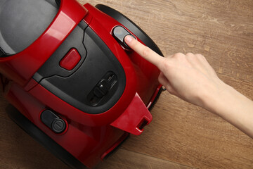 Fototapeta premium Finger presses the button of a red vacuum cleaner
