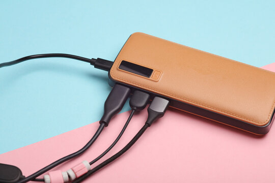 External battery power bank with many usb cables on pink blue background
