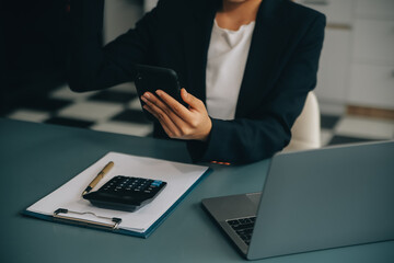 Hispanic businesswoman in formal attire in her office happy and cheerful while using smartphones and working. Young businesswoman using apps on cell phones, reading news, fast connection