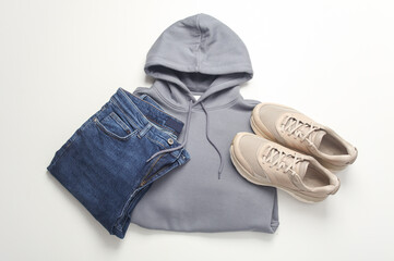 Men's youth clothing style. Jeans, sneakers and hoodie on a white background. Flat lay. Top view