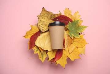 Coffee cardboard cup on autumn leaves, pink background