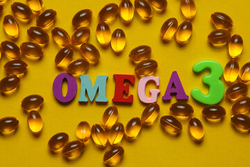 Fish oil capsules and word omega 3 on yellow background.